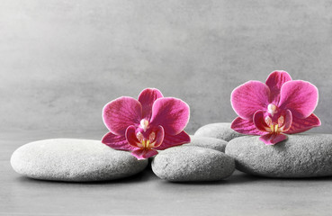 Fototapeta na wymiar Spa stones and orchid flower on the grey background