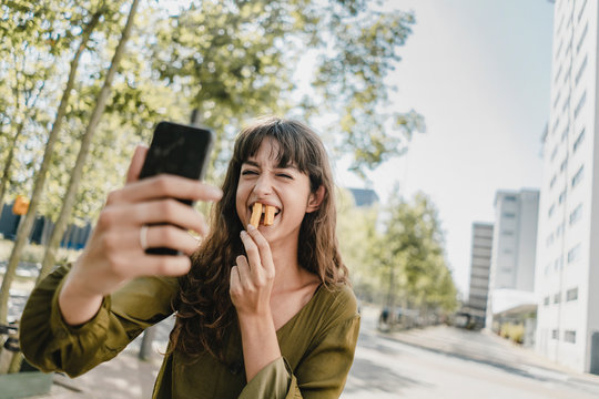 Portrait of brunette woman, taking a selfie, rabbit teeth with french fries