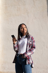 Portrait of African American young beautiful woman standing on the street while using a mobile phone