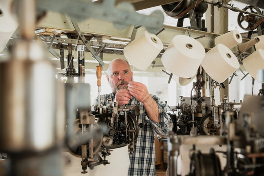 Worker adjusting circular knitting machine, threading yarn