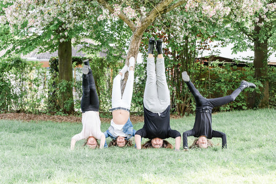 Mother with three triplet daughters doing a headstand on a meadow