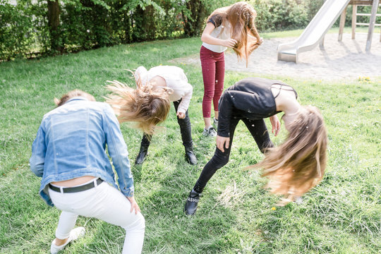 Four girls shaking their heads covered with dandelion seeds