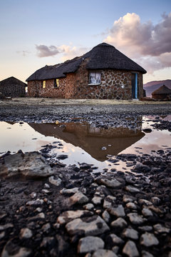 Traditional stone houses and reflection in a puddle, Lesotho