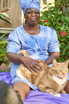 Senior woman with a cat sitting on a blanket in garden