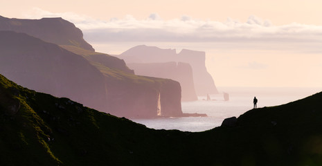 Man silhouette on background of famous Risin og Kellingin rocks and cliffs of Eysturoy and Streymoy...