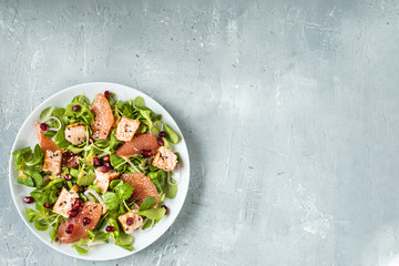 Healthy eating, grilled salmon, arugula, grapefruit and pomegranate on gray table, top view