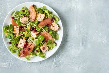 Healthy eating, grilled salmon, arugula, grapefruit and pomegranate on gray table, top view