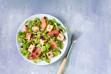 Healthy eating, grilled salmon, arugula, grapefruit and pomegranate on gray table, top view