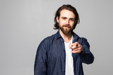 Portrait of a smiling satisfied man pointing at camera isolated on a gray background