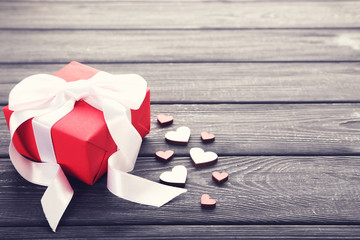 Gift box with ribbon and hearts on black wooden table