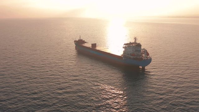 Aerial view. Beatiful sunset at the sea. Huge cargo ship floating in the sea.
