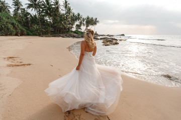 Fototapeta na wymiar Happy young bride woman in white dress running, have fun on clean sandy beach waves of azure sea or ocean on sunset, summer vacation at water. Wedding rest, relax honeymoon concept