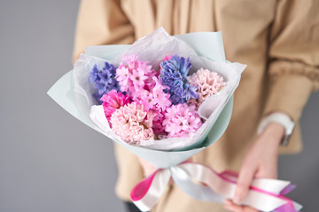 Young happy woman holding a beautiful bunch of colorful hyacinths in her hands. Present for a smiles girl. Flowers bouquet.