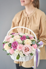 Flowers delivery. Flower arrangement in Wicker basket. Beautiful bouquet of mixed flowers in woman hand. Floral shop concept . Handsome fresh bouquet.