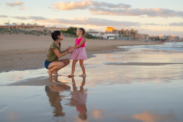 Happy family. Young happy beautiful mother and her daughter having fun on the beach at sunset. Positive human emotions, feelings