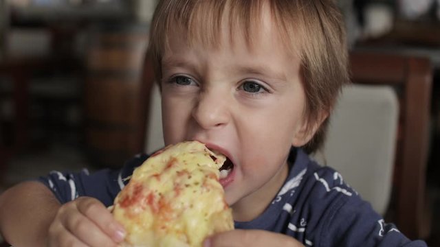 Close up of little cute boy eating pizza. Neutral colors for collor correction.