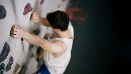 athletischer Mann beim Bouldern an Kletterwand
