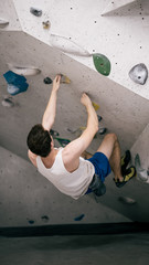 athletischer Mann über Kopf beim Bouldern an Kletterwand