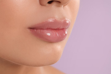 Young woman with beautiful full lips on lilac background, closeup