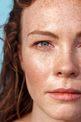 Summer Freestyle. Young woman with freckles standing isolated on blue looking camera pensive close-up