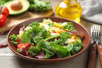 Tasty fresh kale salad on wooden table, closeup