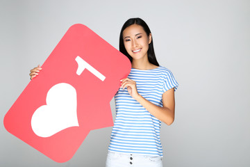 Beautiful woman holding paper card with heart and number one on grey background