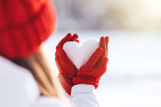 Woman In Red Gloves And Hat Holding Heart Shape From Snow, Valentines Day, Sun Set. Love Concept.