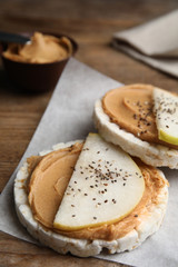 Puffed rice cakes with peanut butter and pear on wooden table