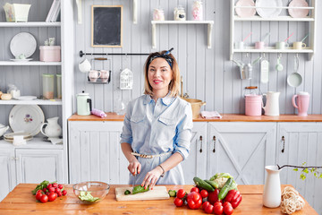 Beautiful young woman is preparing vegetable salad in the kitchen. Healthy Food. Cooking at home. Dieting Concept.