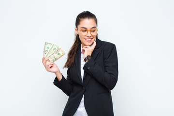 young businesswoman smiling with a happy, confident expression with hand on chin, wondering and looking to the side with banknotes with bills © kues1