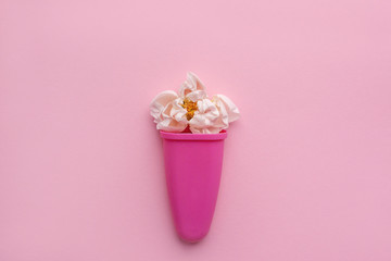 Rose bud in a plastic cup of ice cream on a pink background. Space for text. flower composition