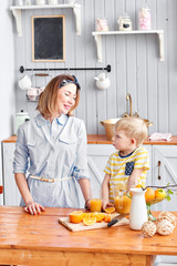 Mother and son are smiling while having a breakfast in kitchen. Bright morning in the kitchen. Healthy Breakfast cereals and fresh fruit.