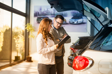 Car dealer presenting new car to the customer. Vehicle dealership.