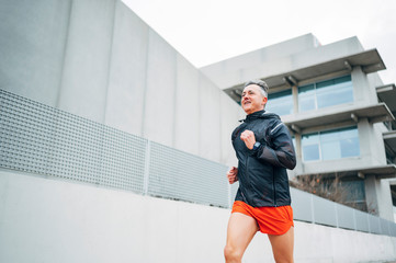 Senior retired man runs and performs exercise