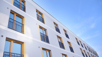 Obraz premium Contemporary residential building exterior in the daylight. Modern apartment buildings on a sunny day with a blue sky. Facade of a modern apartment building