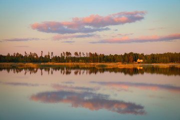 Naklejka premium summer landscape blue lake on the background of the forest, pink cloud on the sky