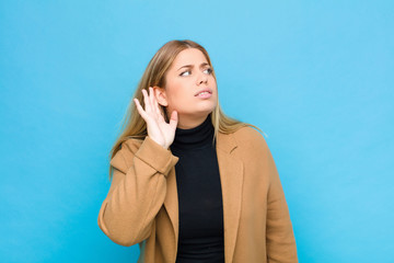 young blonde woman looking serious and curious, listening, trying to hear a secret conversation or...