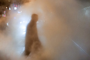 Outline of man walking through a steam stack in New York City, with cars in background