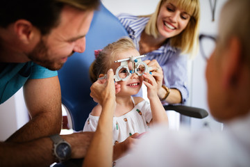 Ophthalmologist is checking the eye vision of little cute girl in modern clinic.