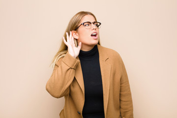 young blonde woman looking serious and curious, listening, trying to hear a secret conversation or...
