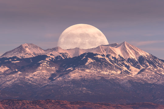 Full moon at it's perigee rising behind La Sal Mountains in Canyonlands National Park during sunset