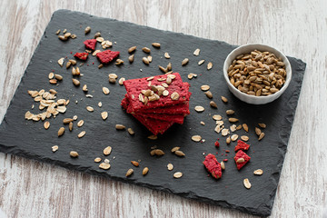 Healthy snack cracker or biscuit with seeds and beetroot top view on a stone plate with oat flakes on wooden background, healthy eating or dieting concept