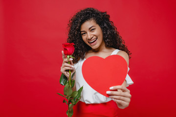 attractive black woman with heart shaped valentine card and rose isolated over red