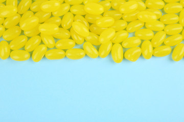 Many delicious lemon jelly beans on light blue background, flat lay. Space for text