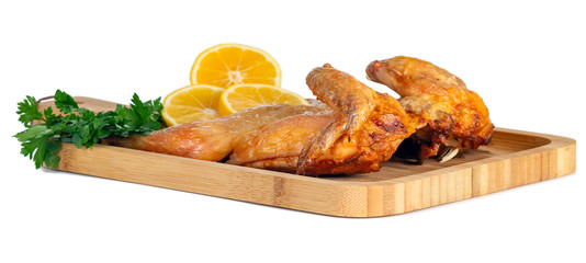fried chicken on a wooden bord with parsley and lemon on white background