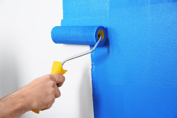 Man painting white wall with blue dye, closeup. Interior renovation