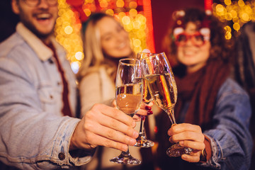 Close view of group of happy friends drinking champagne and celebrating New Year at the street. New year party.