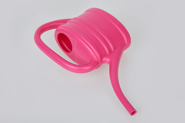 Small pink plastic watering can isolated on white background. 