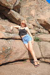 Young blonde in dark glasses on granite stones