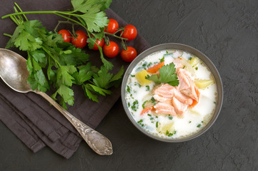 Salmon soup with cream, potatoes, carrots and dill. on a black background.